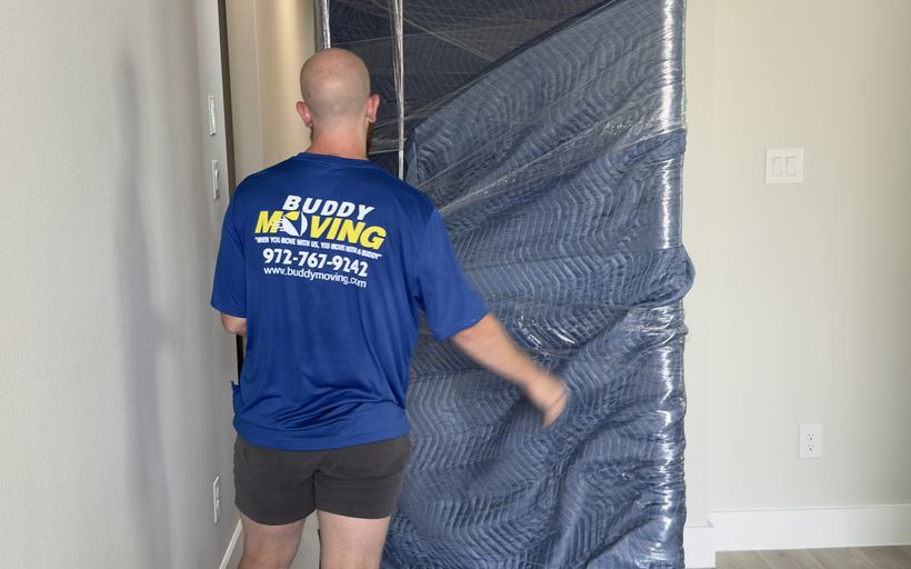 Two Buddy Moving crew members wrapping furniture